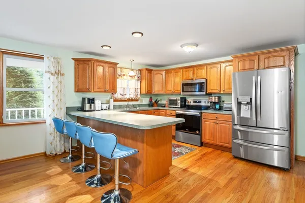 a kitchen with stainless steel appliances granite countertop a stove a refrigerator a sink a stove and island with wooden floor