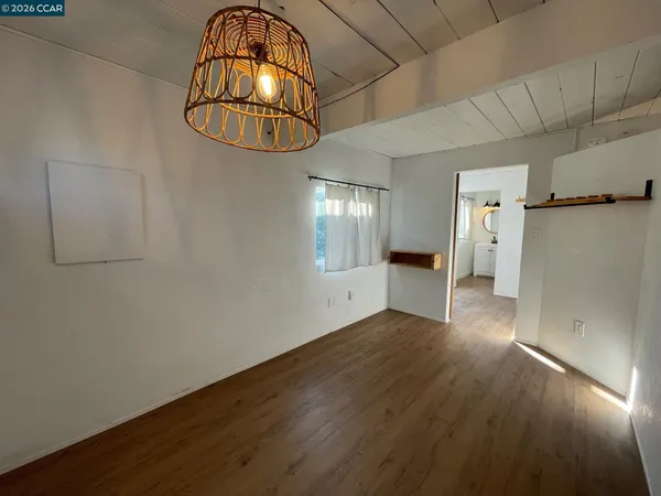 an empty room with wooden floor and chandelier