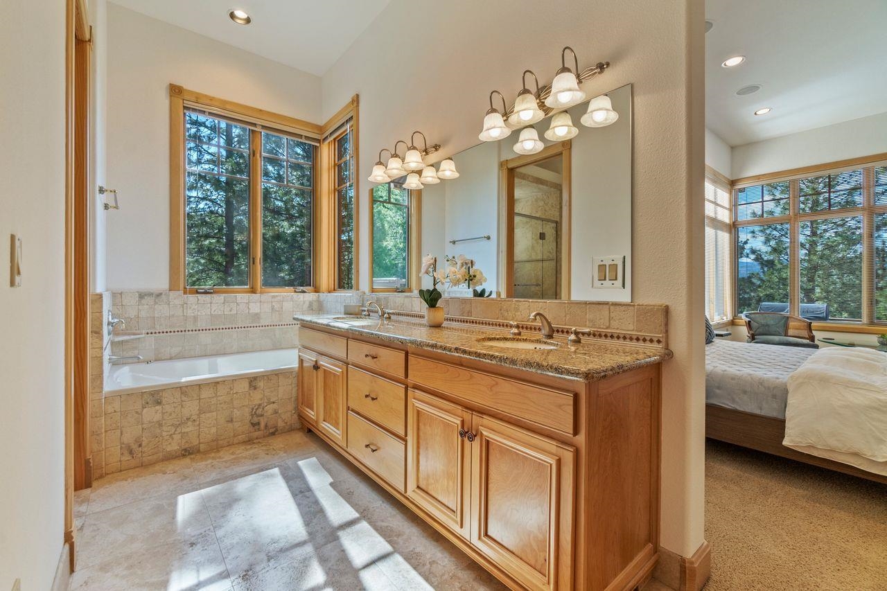 759 Red Sky Clio, CA 96106 - Photo 12 of 21 a bathroom with a granite countertop sink a large mirror and a bathtub next to a window