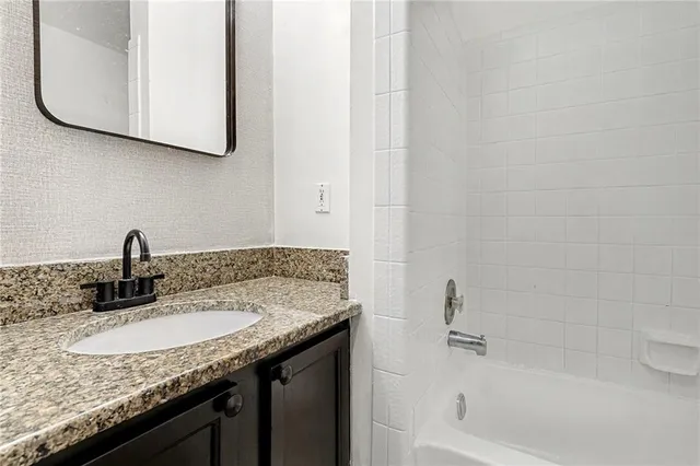 a bathroom with a granite countertop sink and a mirror
