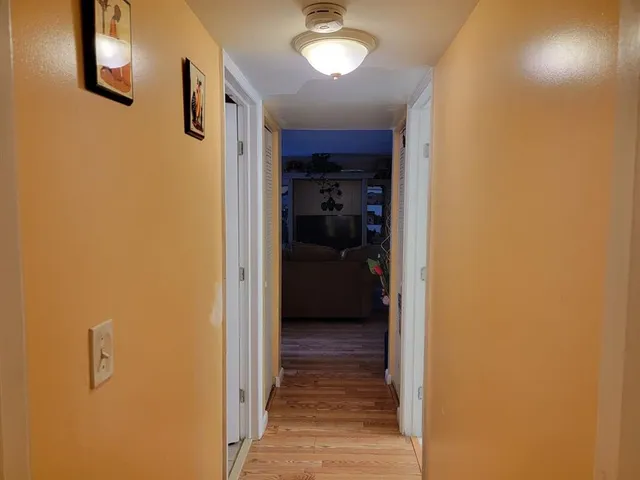 a view of a hallway with wooden floor and closet