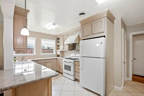 a kitchen with granite countertop a refrigerator a sink and white cabinets