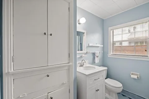 a bathroom with a toilet a sink a vanity and window