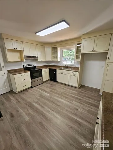 a kitchen with stainless steel appliances kitchen island granite countertop a stove a sink and white cabinets