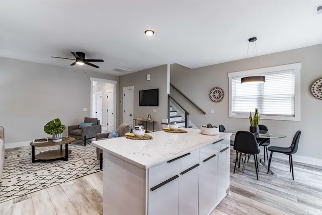 a living room with stainless steel appliances kitchen island granite countertop furniture a rug and a window