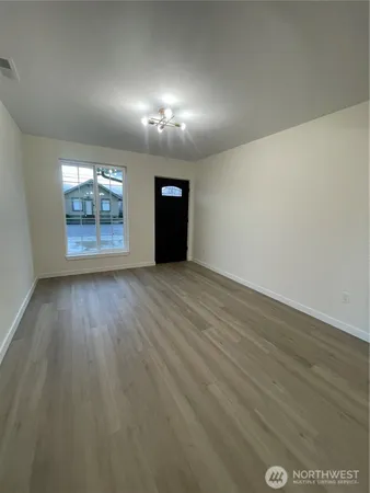 an empty room with wooden floor and windows
