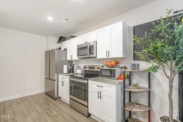 a kitchen with stainless steel appliances a refrigerator stove and white cabinets
