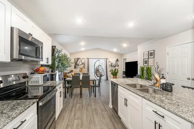 a kitchen with granite countertop lots of counter top space a sink appliances and cabinets