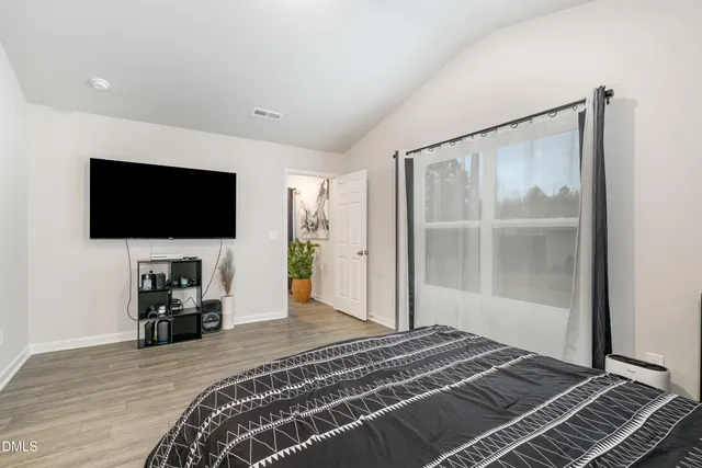 a bedroom with a bed and a flat tv screen on the dresser