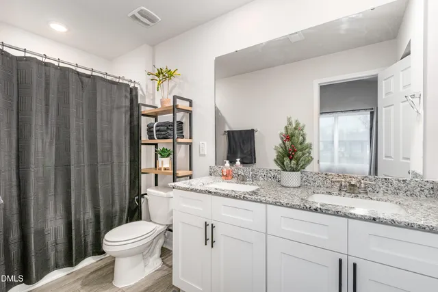 a bathroom with a granite countertop sink a toilet and a large mirror