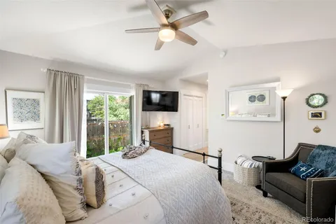 a bedroom with a bed couches and a flat tv screen