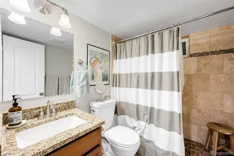 a bathroom with a granite countertop sink mirror vanity and toilet