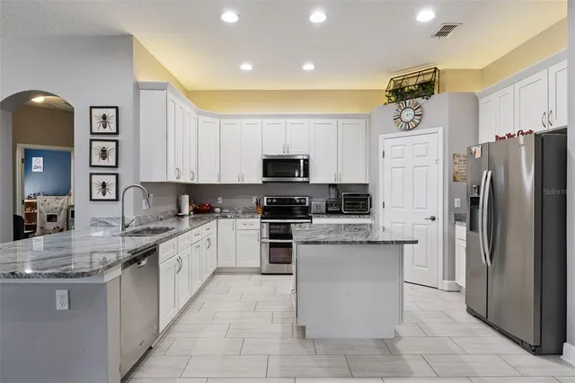 a kitchen with stainless steel appliances granite countertop a refrigerator and a stove top oven