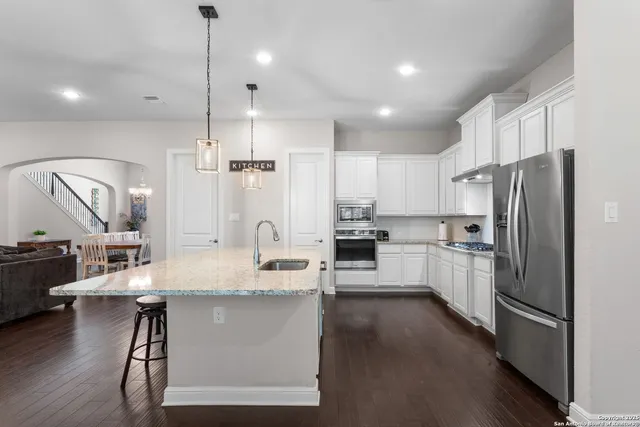 a large kitchen with a center island wooden floor stainless steel appliances and windows