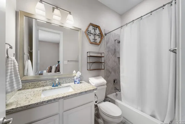 a bathroom with a granite countertop sink toilet a mirror and shower