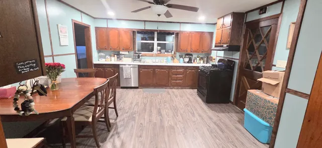 a kitchen with stainless steel appliances granite countertop a refrigerator a sink dishwasher a stove and a dining table with wooden floor