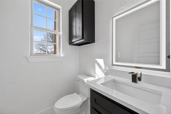 a bathroom with a granite countertop sink toilet and mirror