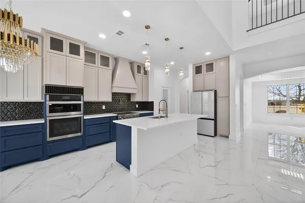 a large white kitchen with stainless steel appliances granite countertop a stove and a refrigerator