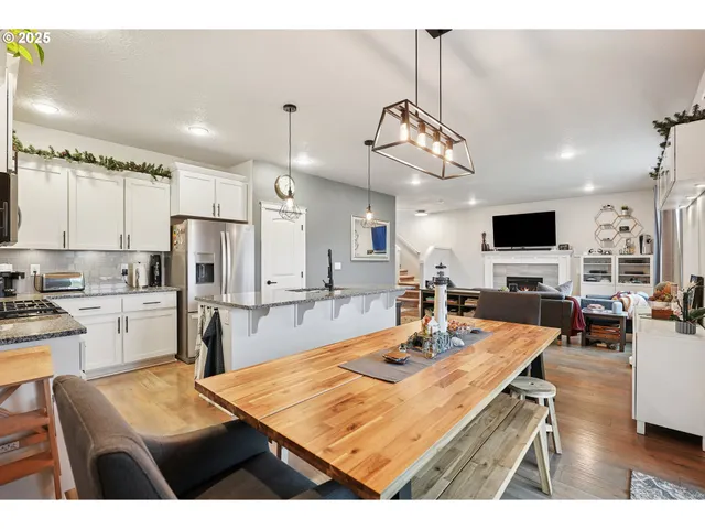 a kitchen with stainless steel appliances kitchen island granite countertop a table chairs and a refrigerator