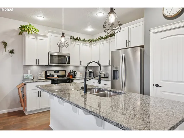 a kitchen with stainless steel appliances granite countertop a sink refrigerator and microwave