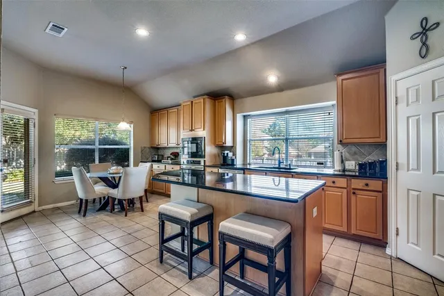 a dining hall with stainless steel appliances granite countertop a stove a refrigerator a table and chairs