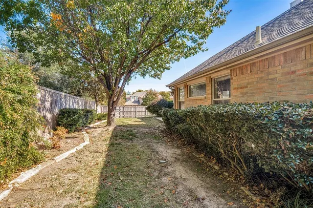 a backyard of a house with large trees and plants
