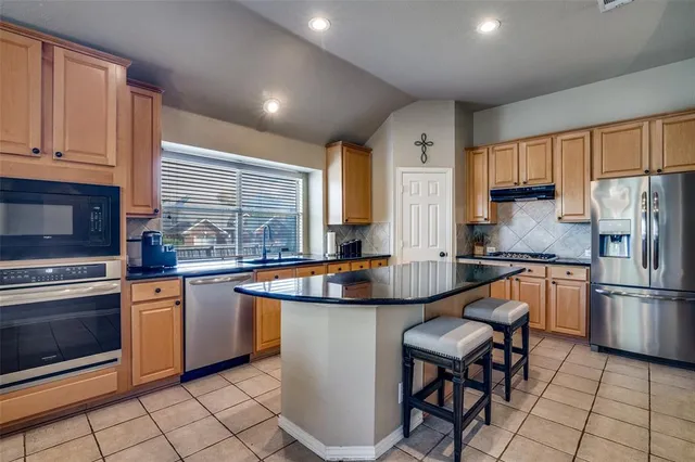 a kitchen with stainless steel appliances granite countertop a stove a sink a refrigerator and a microwave