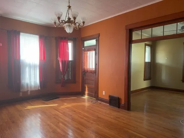 an empty room with wooden floor and windows