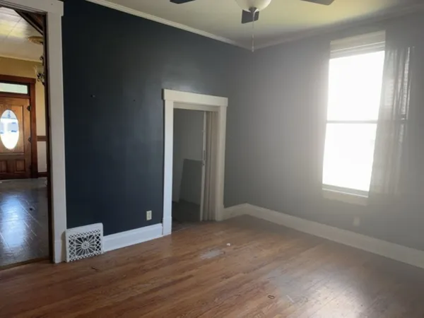 an empty room with wooden floor and windows