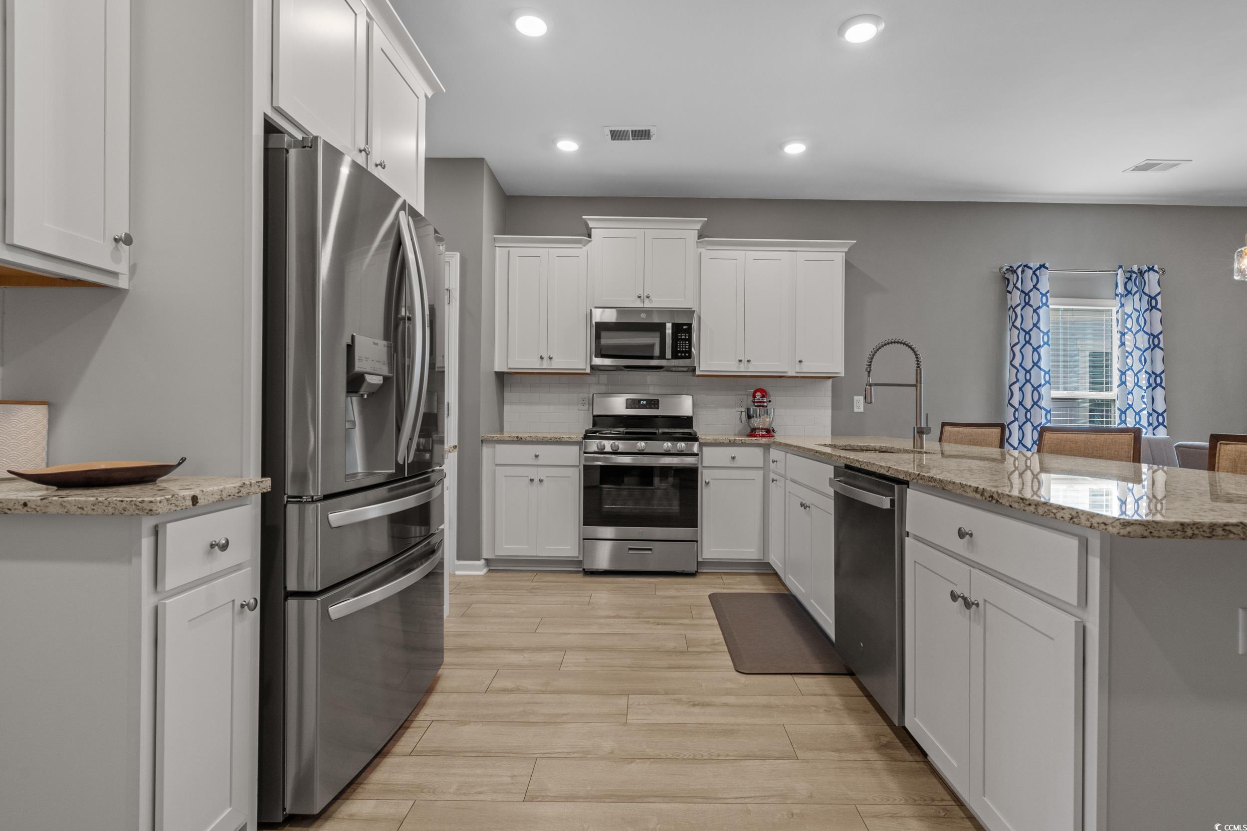 5575 Whitebark Drive Myrtle Beach, SC 29577 - Photo 9 of 39 Kitchen featuring stainless steel appliances, light stone countertops, white cabinetry, tasteful backsplash, and recessed lighting