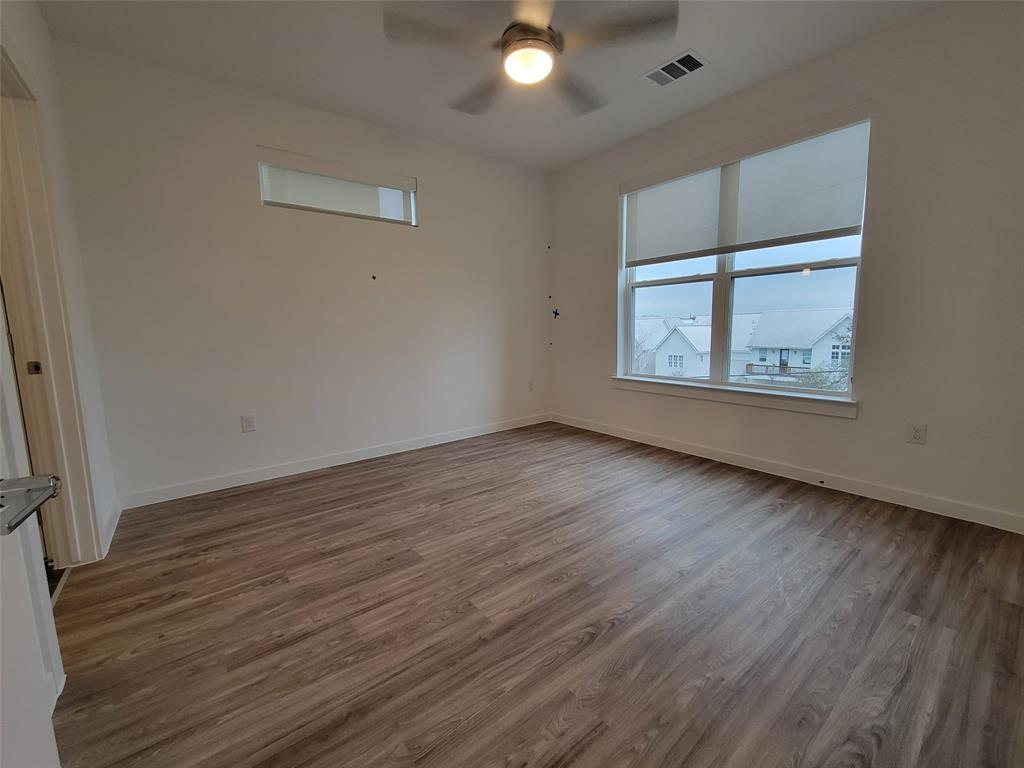4801 Springdale Road, Unit 2211 Austin, TX 78723 - Photo 11 of 19 A generous space illuminated by ample windows, featuring warm wood flooring and a modern ceiling fan.