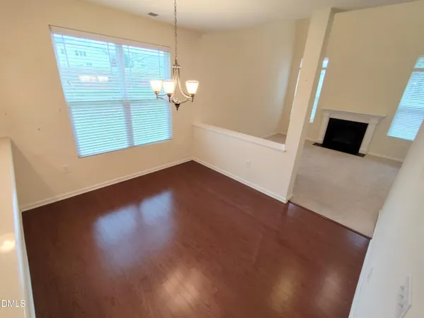an empty room with wooden floor cabinet and windows