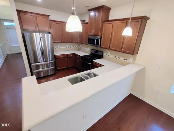 a kitchen with stainless steel appliances a sink a stove a refrigerator and island