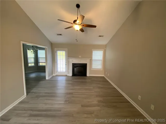 a view of a livingroom with a fireplace a chandelier and wooden floor