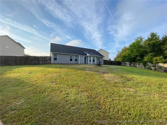 a view of a large pool with lawn chairs and large trees
