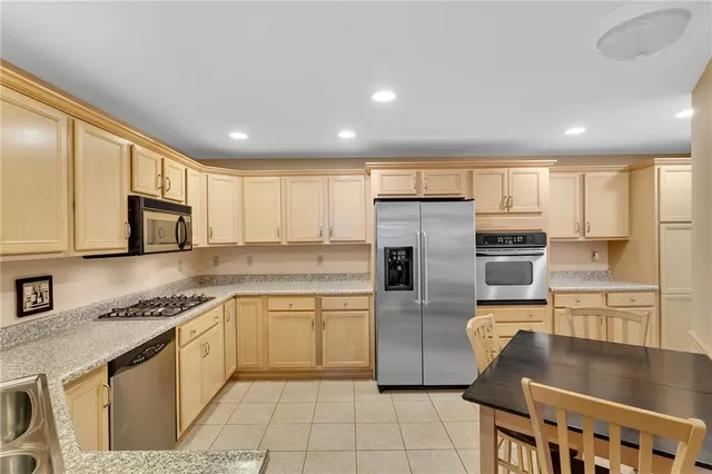 a kitchen with stainless steel appliances granite countertop a refrigerator a stove and a sink with wooden floor