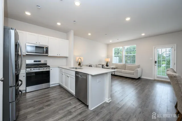 a kitchen with stainless steel appliances granite countertop wooden floors a stove and a sink