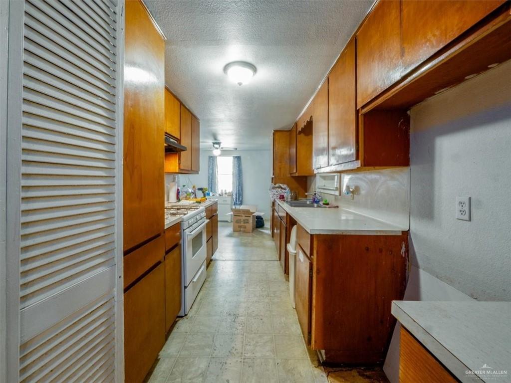 23067 Cragon Road Harlingen, TX 78552 - Photo 7 of 28 a kitchen with wooden cabinets and a sink