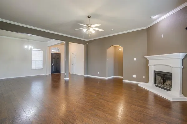 a view of an empty room with wooden floor and a fireplace