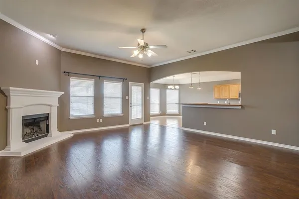 a view of an empty room with wooden floor and a fireplace