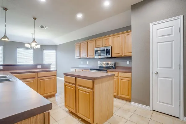 a kitchen with stainless steel appliances granite countertop a stove top oven a refrigerator a sink and dishwasher with white cabinets