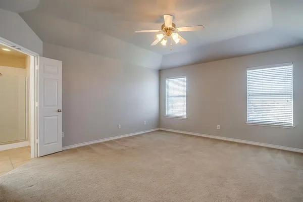 an empty room with chandelier fan and windows