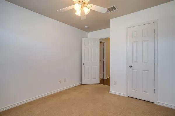 an empty room with a chandelier fan and closet area