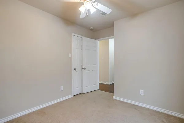 an empty room with a chandelier fan and closet area