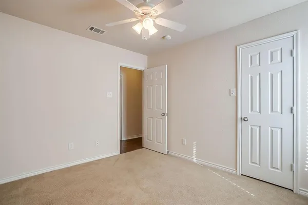 an empty room with closet and a chandelier fan