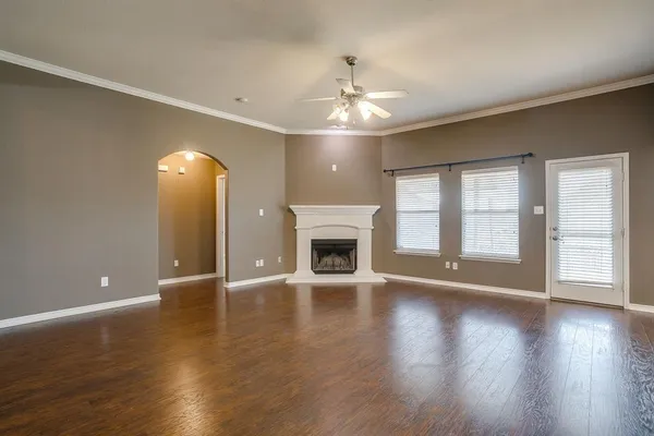 a view of an empty room with wooden floor and a fireplace