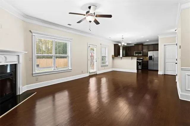 a view of an empty room with kitchen and a window