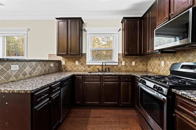 a kitchen with granite countertop a stove top oven microwave and cabinets