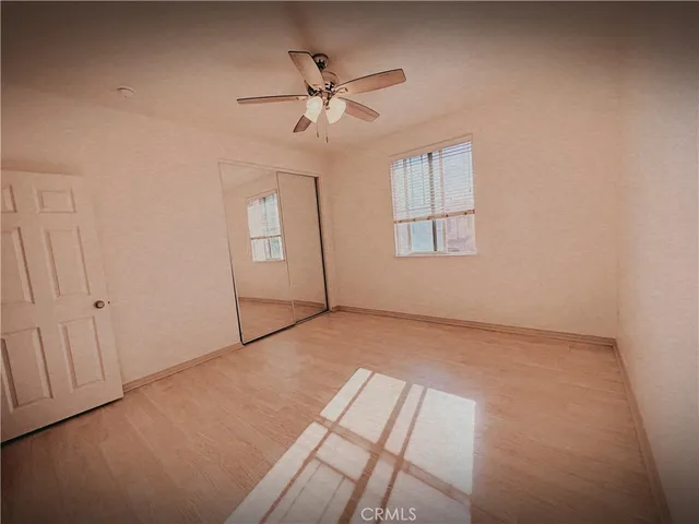 an empty room with chandelier fan and windows