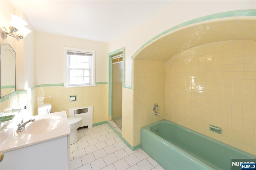 87 Grayson Place Teaneck, NJ 07666 - Photo 12 of 20 a bathroom with a tub a sink and a large mirror